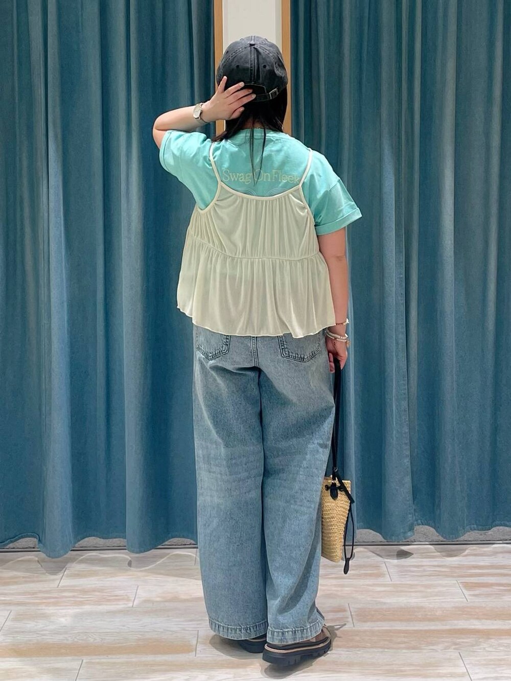 グリーン系のTシャツ/カットソー、ベージュ系のサンダル、ブルー系のデニムパンツを着用したレディースの春コーディネートの2枚目の写真