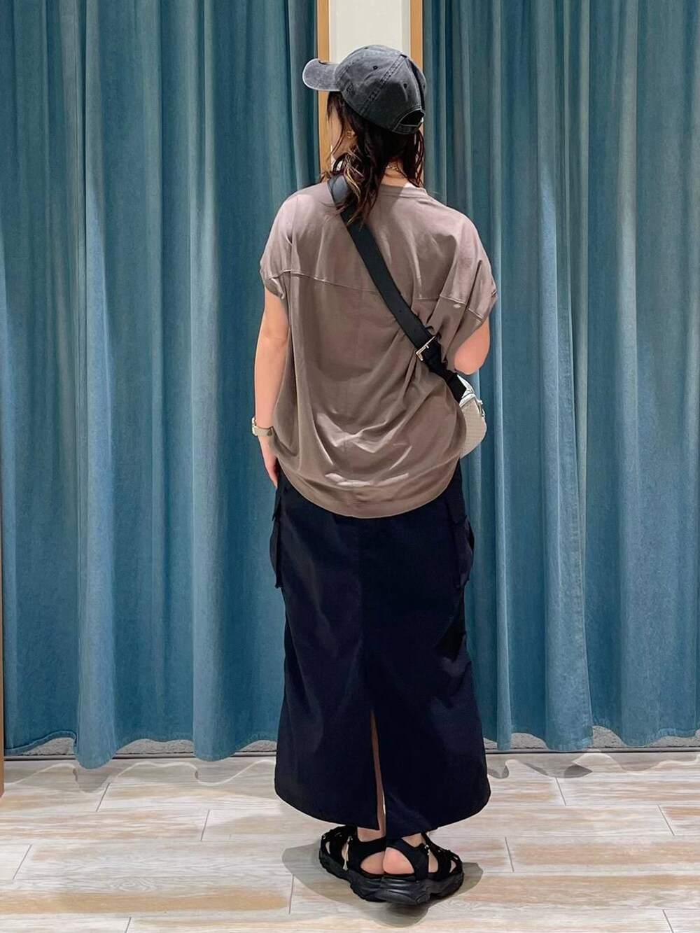 ブラウン系のTシャツ/カットソー、ブラック系のスカート、ブラック系のサンダルを着用したレディースの春コーディネートの3枚目の写真