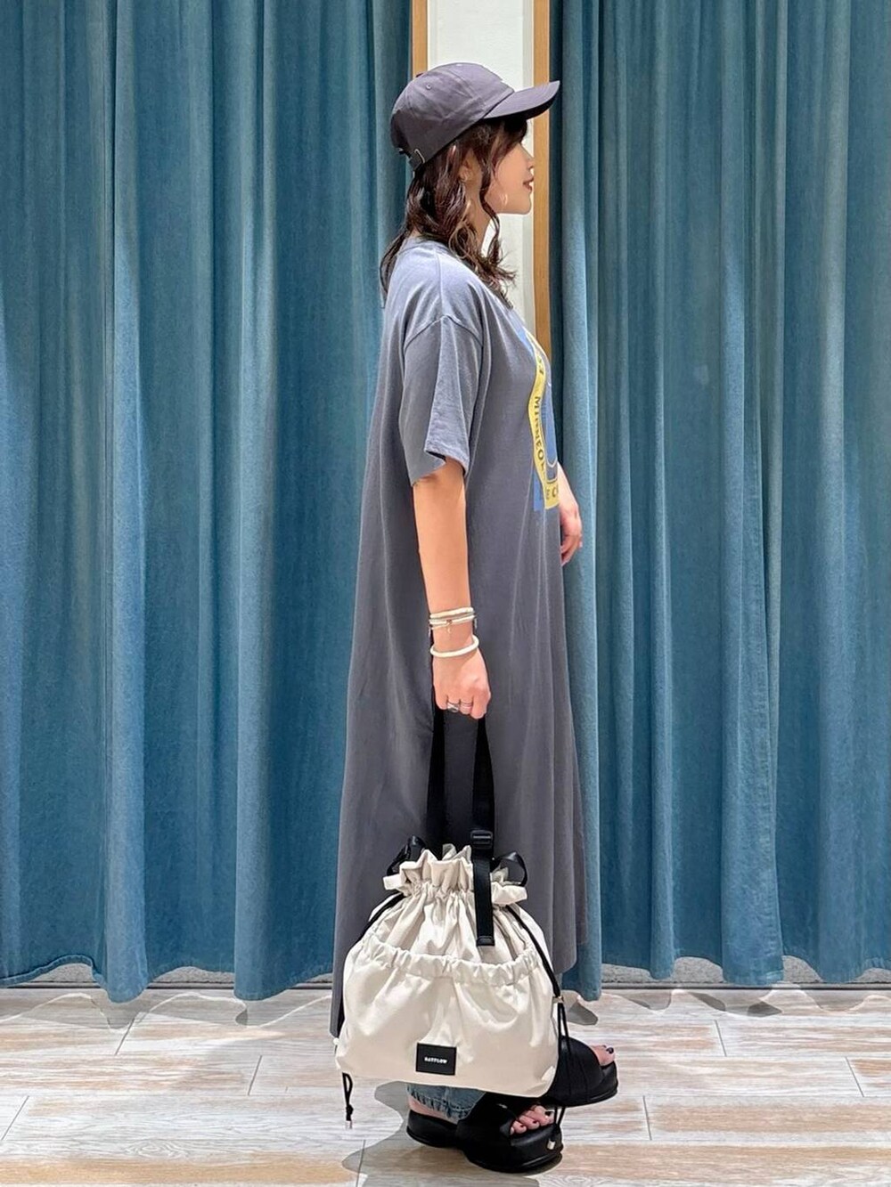 ホワイト系のトートバッグ、ブルー系のデニムパンツ、グレー系のワンピースを着用したレディースの夏コーディネートの2枚目の写真