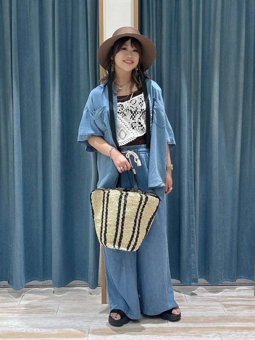 ブルー系のシャツ/ブラウス、ブルー系のデニムパンツ、ベージュ系のトートバッグを着用したレディースの春コーディネートの4枚目の写真