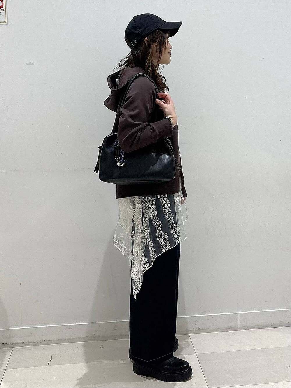 ブラック系のボストンバッグ、ブルー系のデニムパンツ、ブラック系のブーツを着用したレディースの冬コーディネートの2枚目の写真