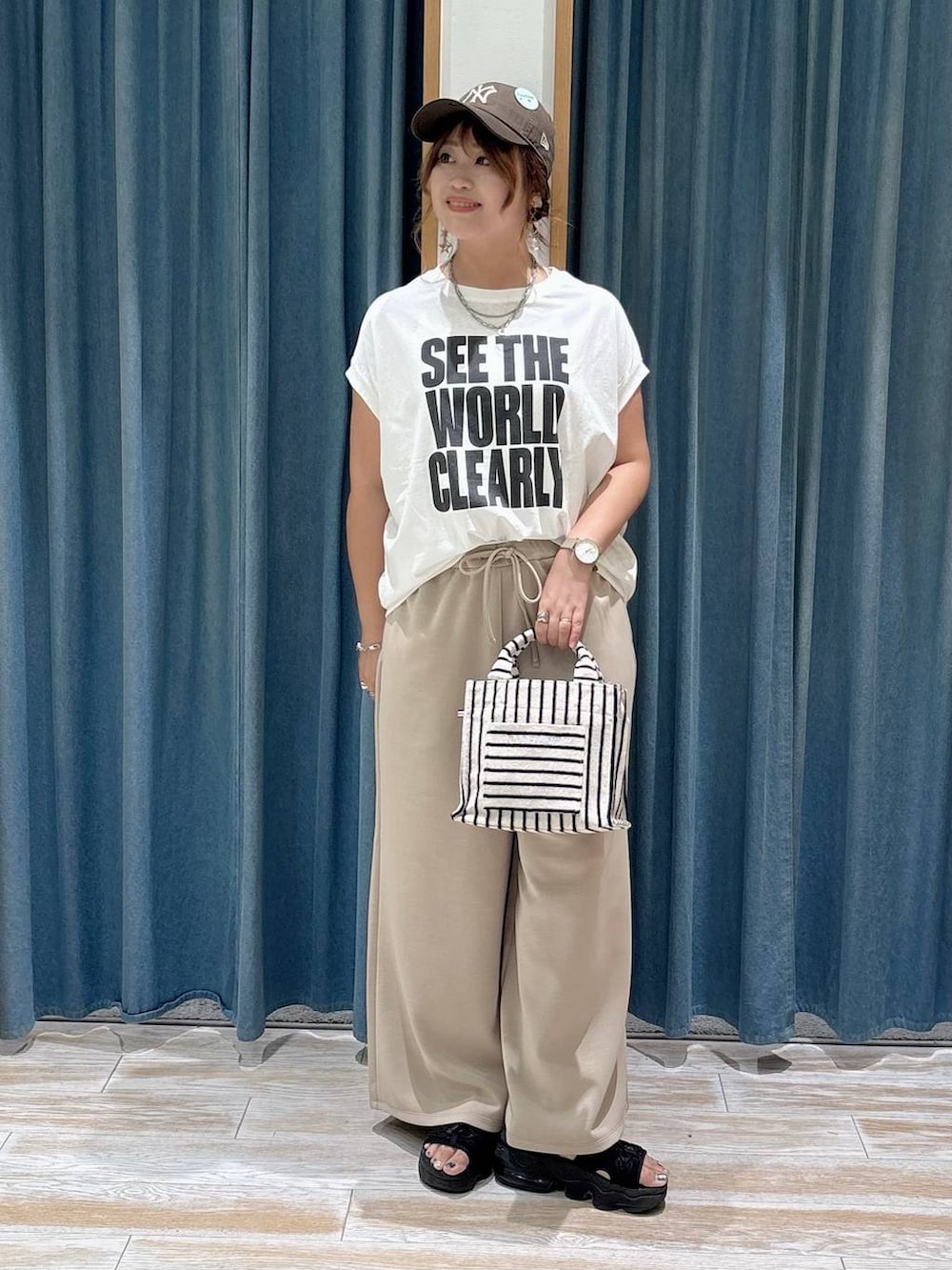 ホワイト系のTシャツ/カットソー、ベージュ系のトートバッグ、ベージュ系のその他パンツを着用したレディースの夏コーディネートの3枚目の写真