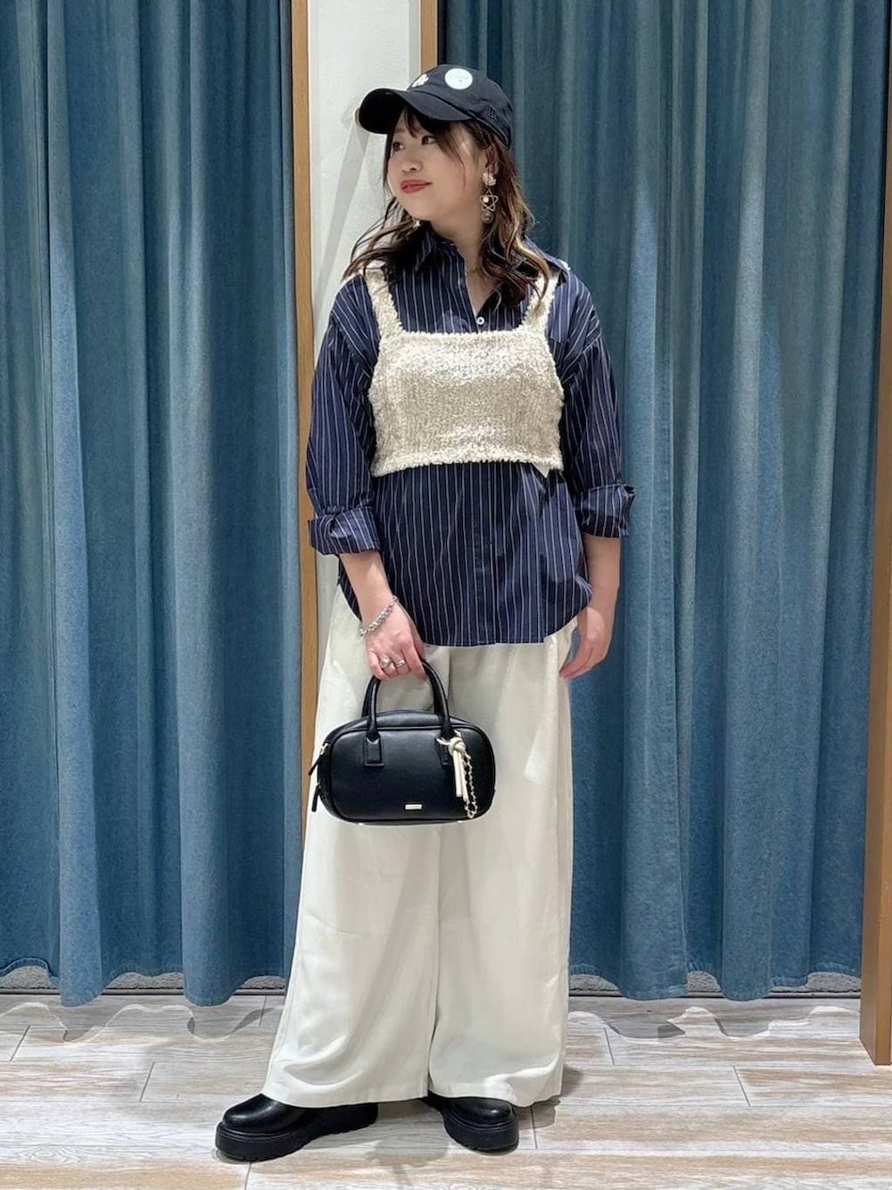 ブラック系のブーツ、ベージュ系のその他トップス、ブラック系のハンドバッグを着用したレディースの春コーディネートの4枚目の写真