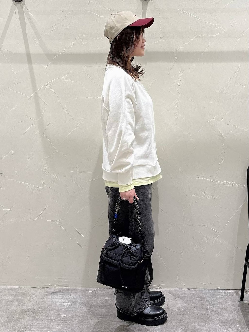 ブラック系のブーツ、ブラック系のショルダーバッグ、ブラック系のデニムパンツを着用したレディースの冬コーディネートの2枚目の写真