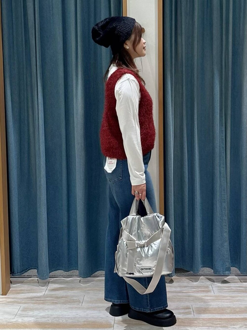 シルバー系のトートバッグ、ホワイト系のTシャツ/カットソー、レッド系のベストを着用したレディースの秋コーディネートの2枚目の写真