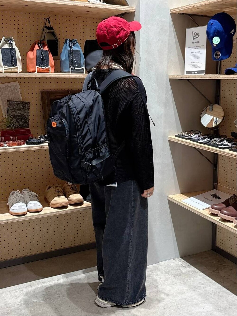 グレー系のデニムパンツ、ブラック系のバックパック/リュック、ブラック系のTシャツ/カットソーを着用したレディースの秋コーディネートの2枚目の写真