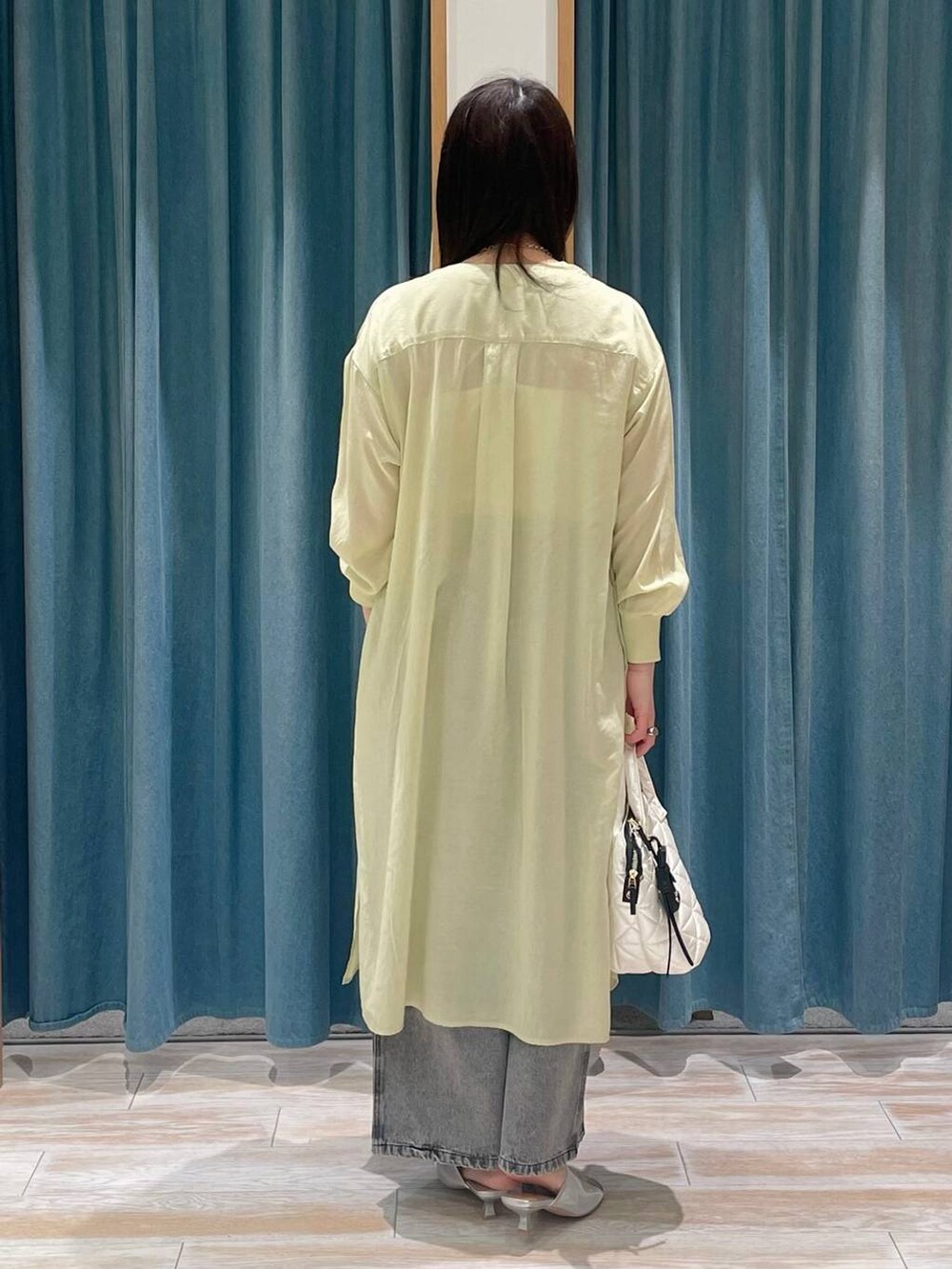 グレー系のデニムパンツ、イエロー系のシャツワンピース、シルバー系のサンダルを着用したレディースの春コーディネートの3枚目の写真