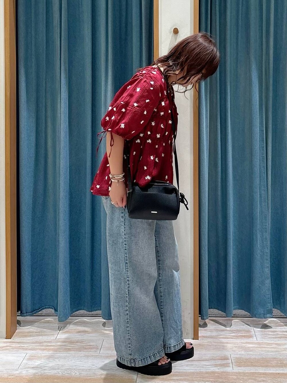 ブルー系のデニムパンツ、ブラック系のショルダーバッグ、レッド系のシャツ/ブラウスを着用したレディースの夏コーディネートの2枚目の写真