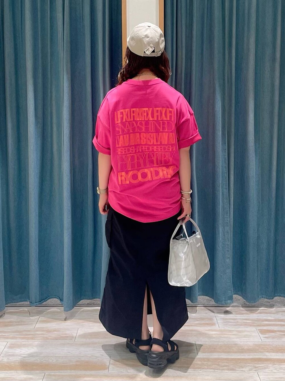ブラック系のスカート、シルバー系のハンドバッグ、ピンク系のTシャツ/カットソーを着用したレディースの春コーディネートの3枚目の写真