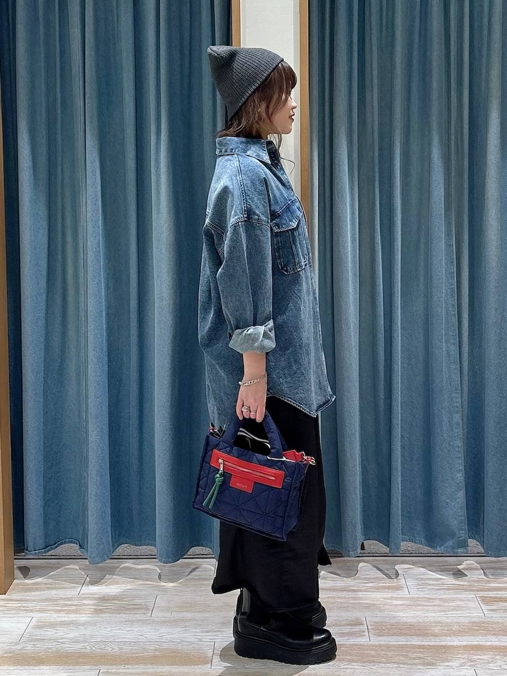 ブルー系のショルダーバッグ、ブラック系のブーツ、ブラック系のスカートを着用したレディースの冬コーディネートの2枚目の写真