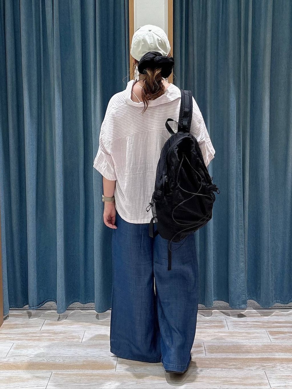 ブラック系のバックパック/リュック、ブルー系のデニムパンツ、ブラック系のサンダルを着用したレディースの夏コーディネートの3枚目の写真