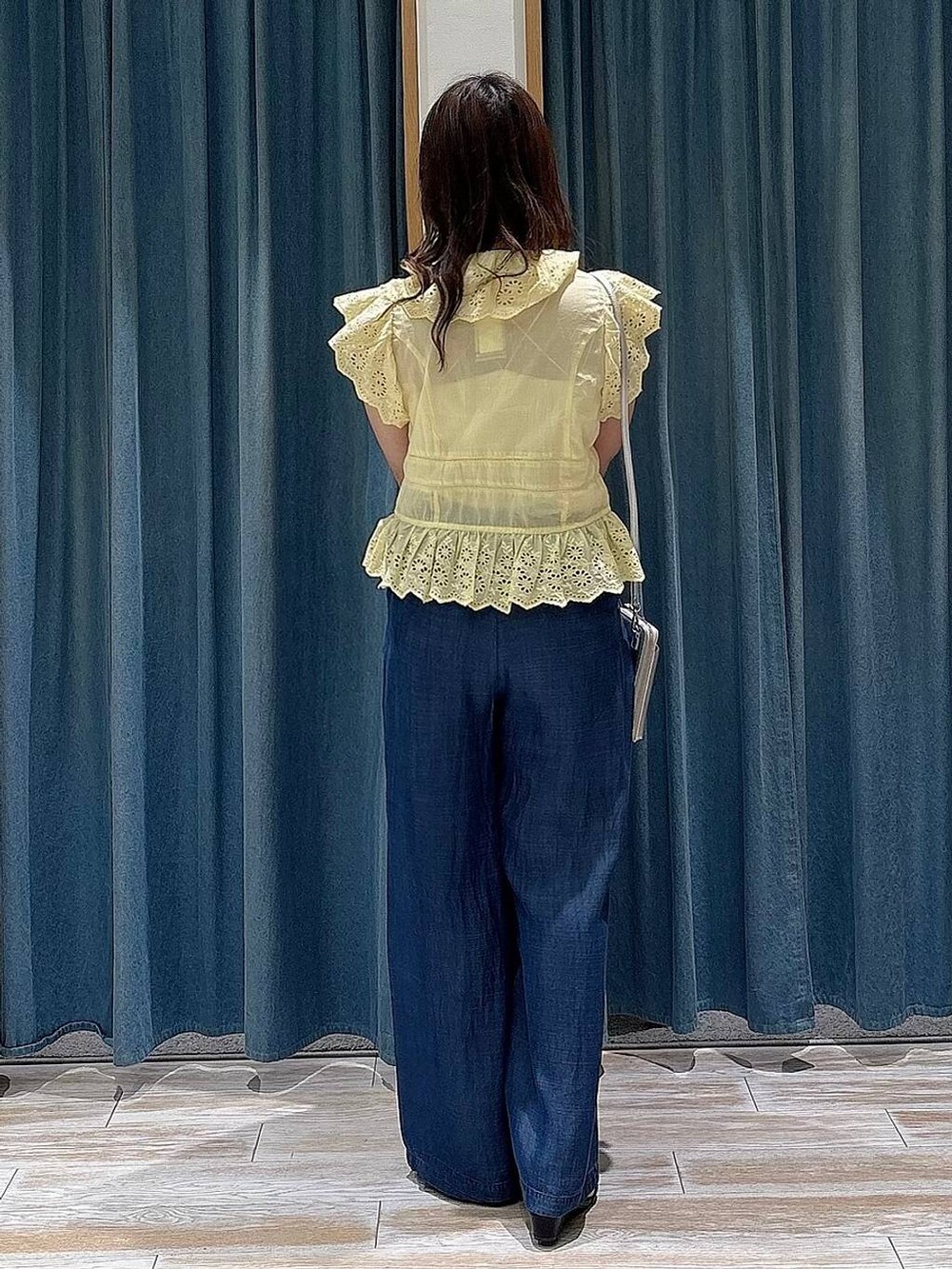 ブルー系のデニムパンツ、イエロー系のシャツ/ブラウス、ブラック系のサンダルを着用したレディースの春コーディネートの2枚目の写真