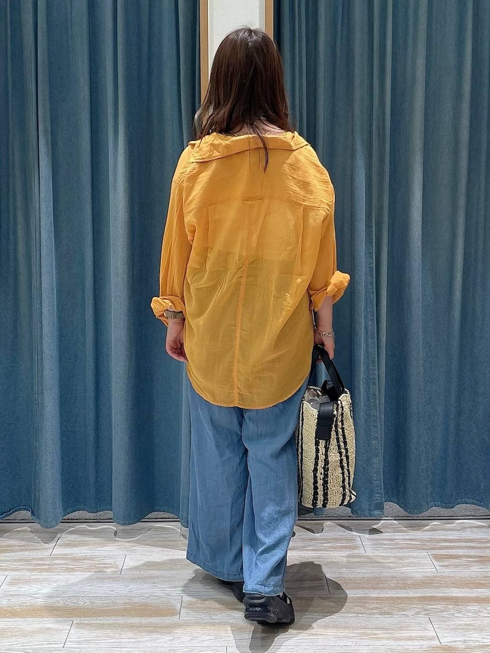 オレンジ系のシャツ/ブラウス、ブルー系のデニムパンツ、ベージュ系のトートバッグを着用したレディースの春コーディネートの3枚目の写真