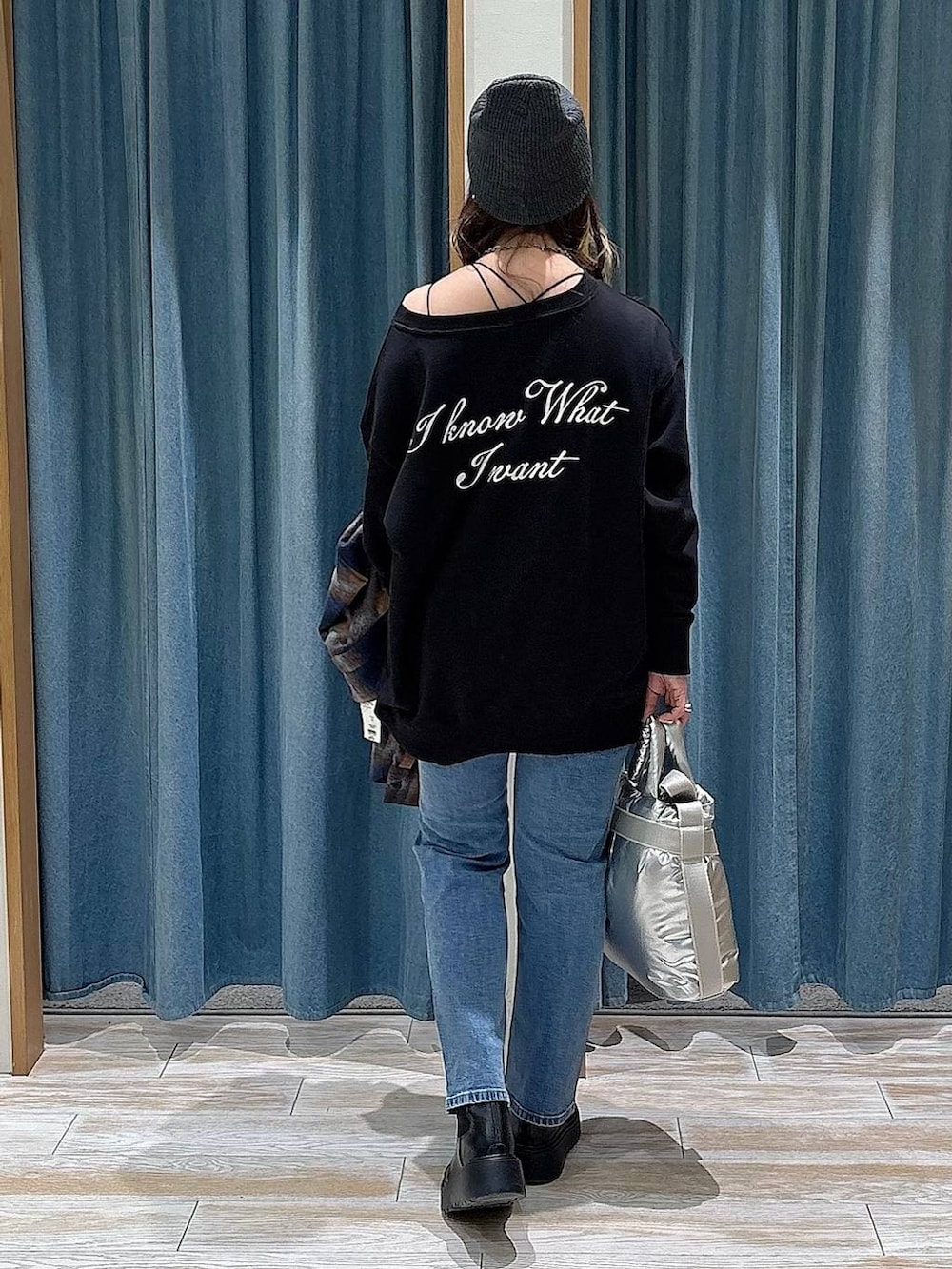 シルバー系のトートバッグ、ブルー系のデニムパンツ、ブラック系のスウェットを着用したレディースの冬コーディネートの3枚目の写真