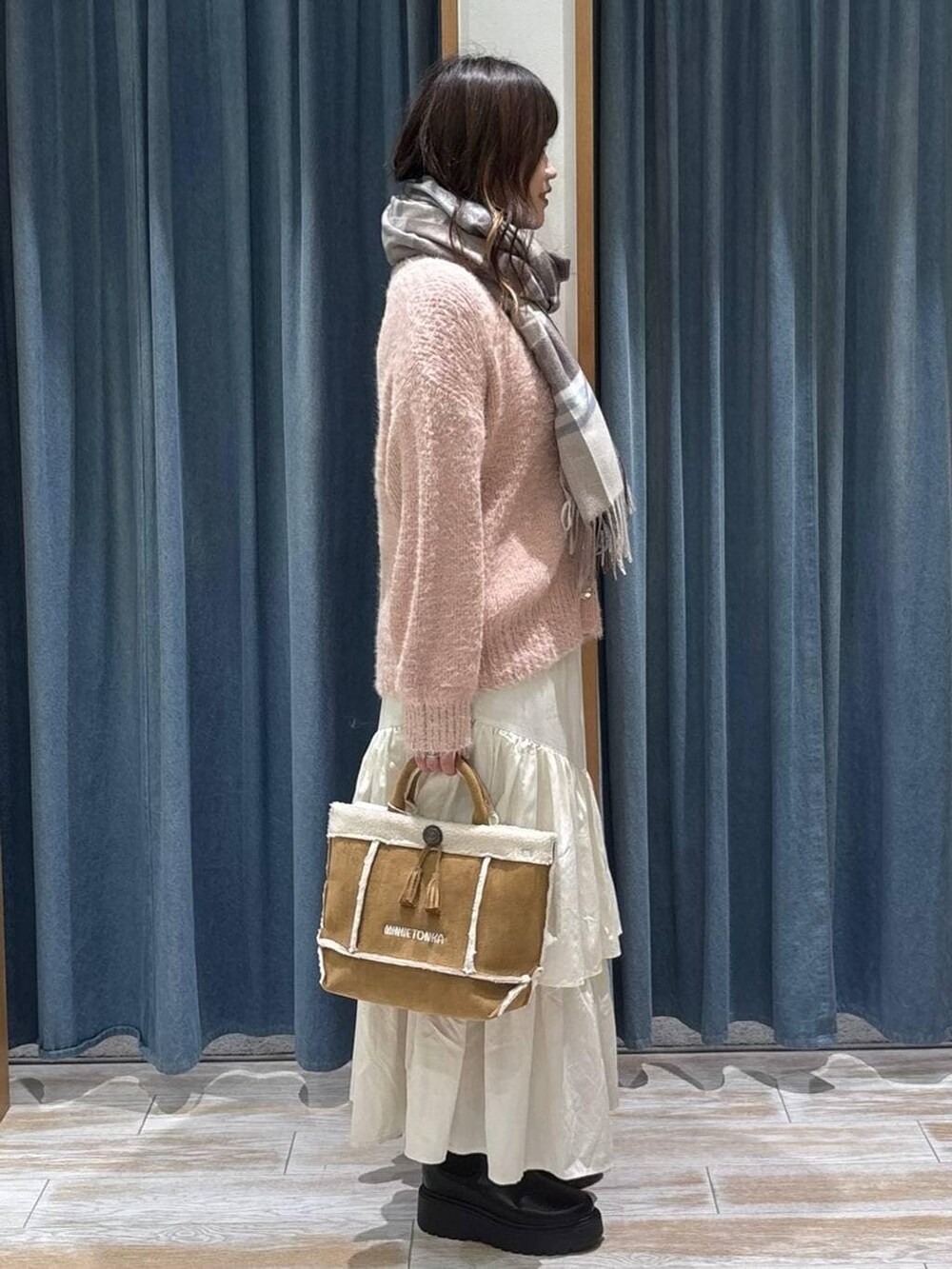 ブラック系のブーツ、イエロー系のショルダーバッグ、ベージュ系のスカートを着用したレディースの冬コーディネートの2枚目の写真