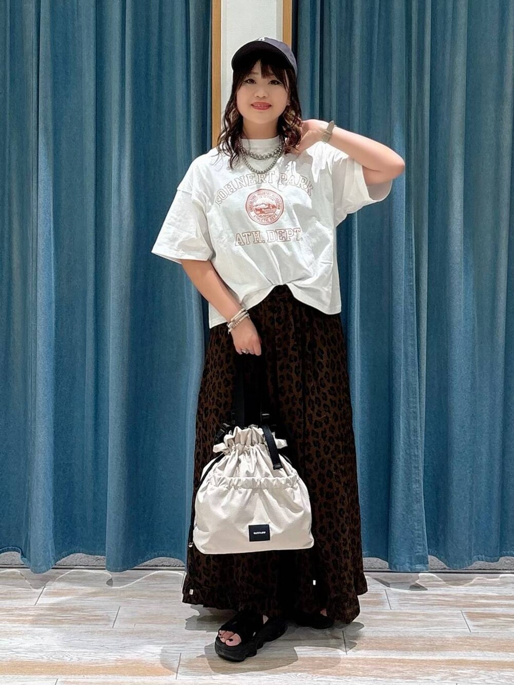 ホワイト系のトートバッグ、ブラウン系のスカート、ホワイト系のTシャツ/カットソーを着用したレディースの夏コーディネートの4枚目の写真