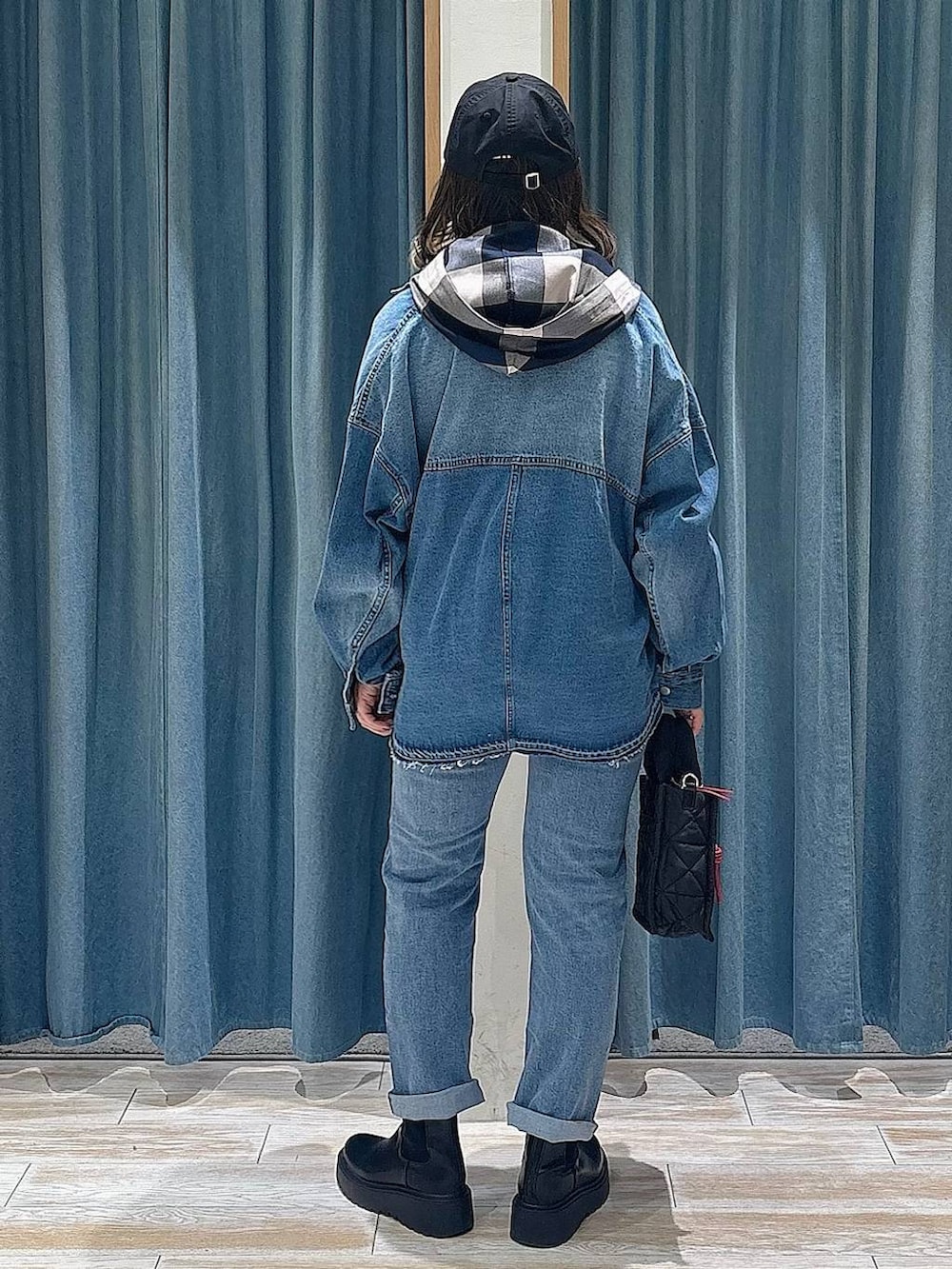 ブラック系のショルダーバッグ、ブラック系のブーツ、ブルー系のデニムパンツを着用したレディースの冬コーディネートの3枚目の写真