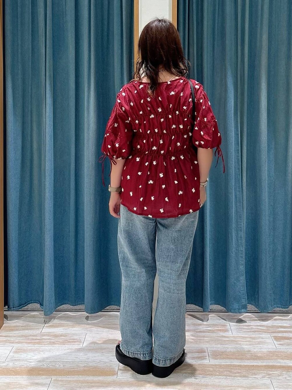 ブルー系のデニムパンツ、ブラック系のショルダーバッグ、レッド系のシャツ/ブラウスを着用したレディースの夏コーディネートの3枚目の写真