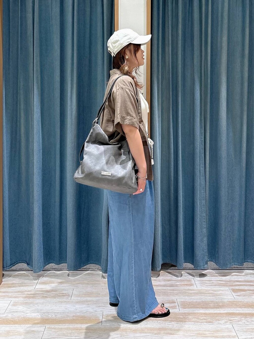 ブルー系のデニムパンツ、グリーン系のシャツ/ブラウス、グレー系のトートバッグを着用したレディースの春コーディネートの2枚目の写真