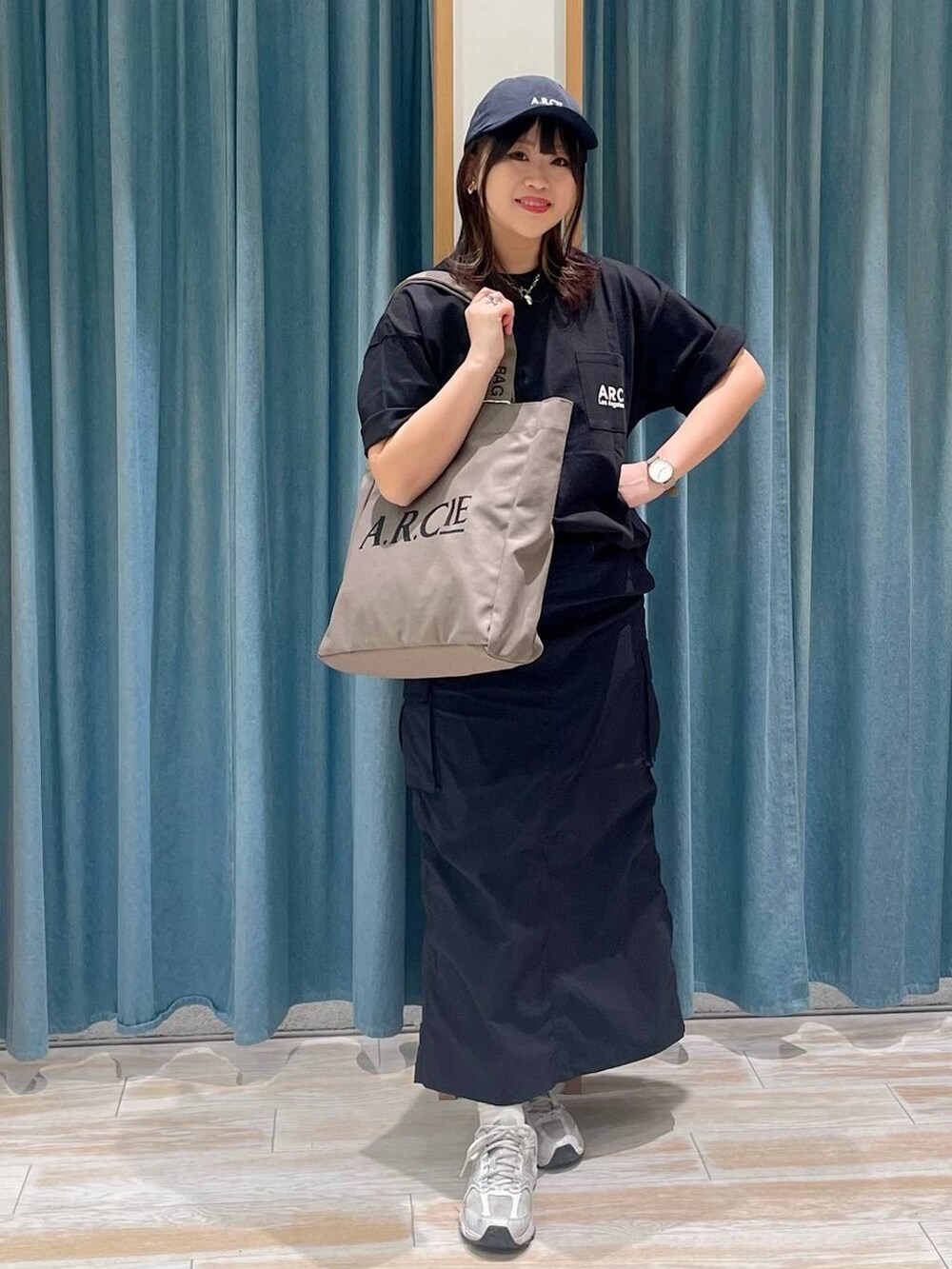 ブラック系のスカート、グリーン系のトートバッグ、ブラック系のTシャツ/カットソーを着用したレディースの春コーディネートの2枚目の写真