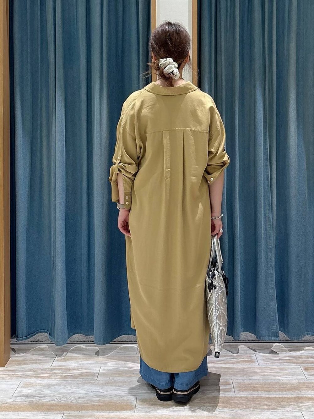 ブルー系のデニムパンツ、イエロー系のワンピース、ブラック系のサンダルを着用したレディースの春コーディネートの3枚目の写真