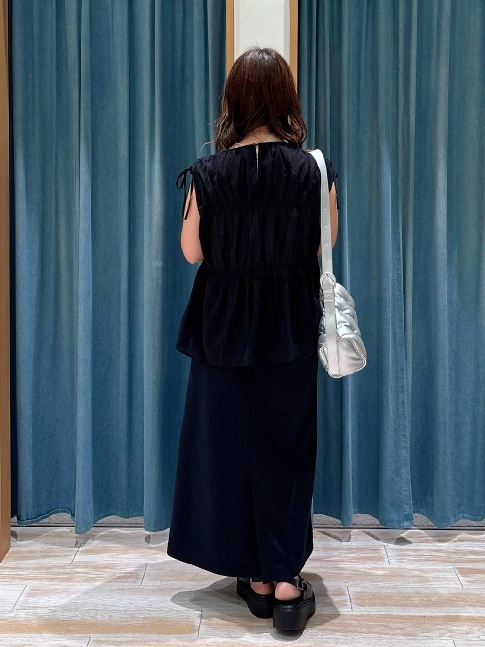 ブラック系のスカート、ブラック系のサンダル、シルバー系のショルダーバッグを着用したレディースの夏コーディネートの2枚目の写真