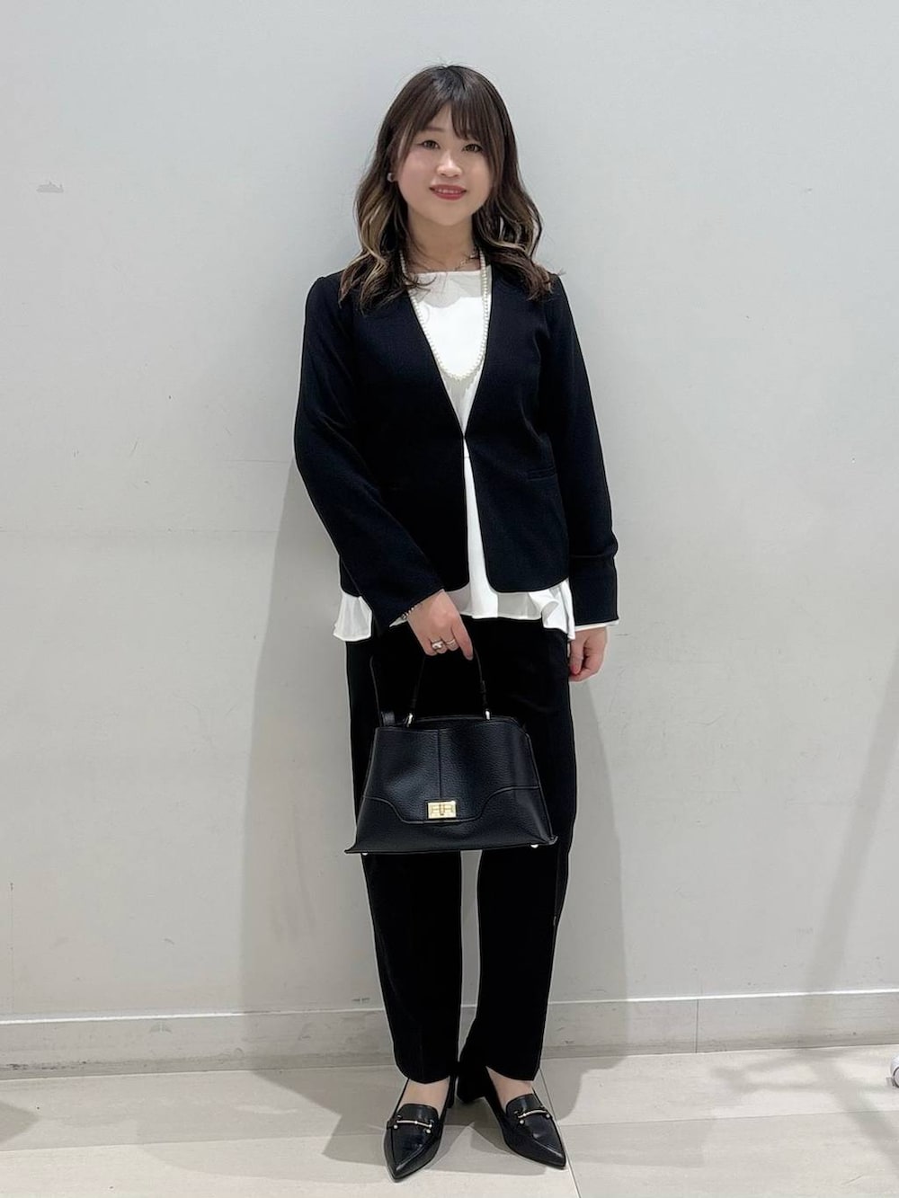 ブラック系のセットアップ、ブラック系のショルダーバッグ、ブラック系のローファーを着用したレディースの冬コーディネートの4枚目の写真