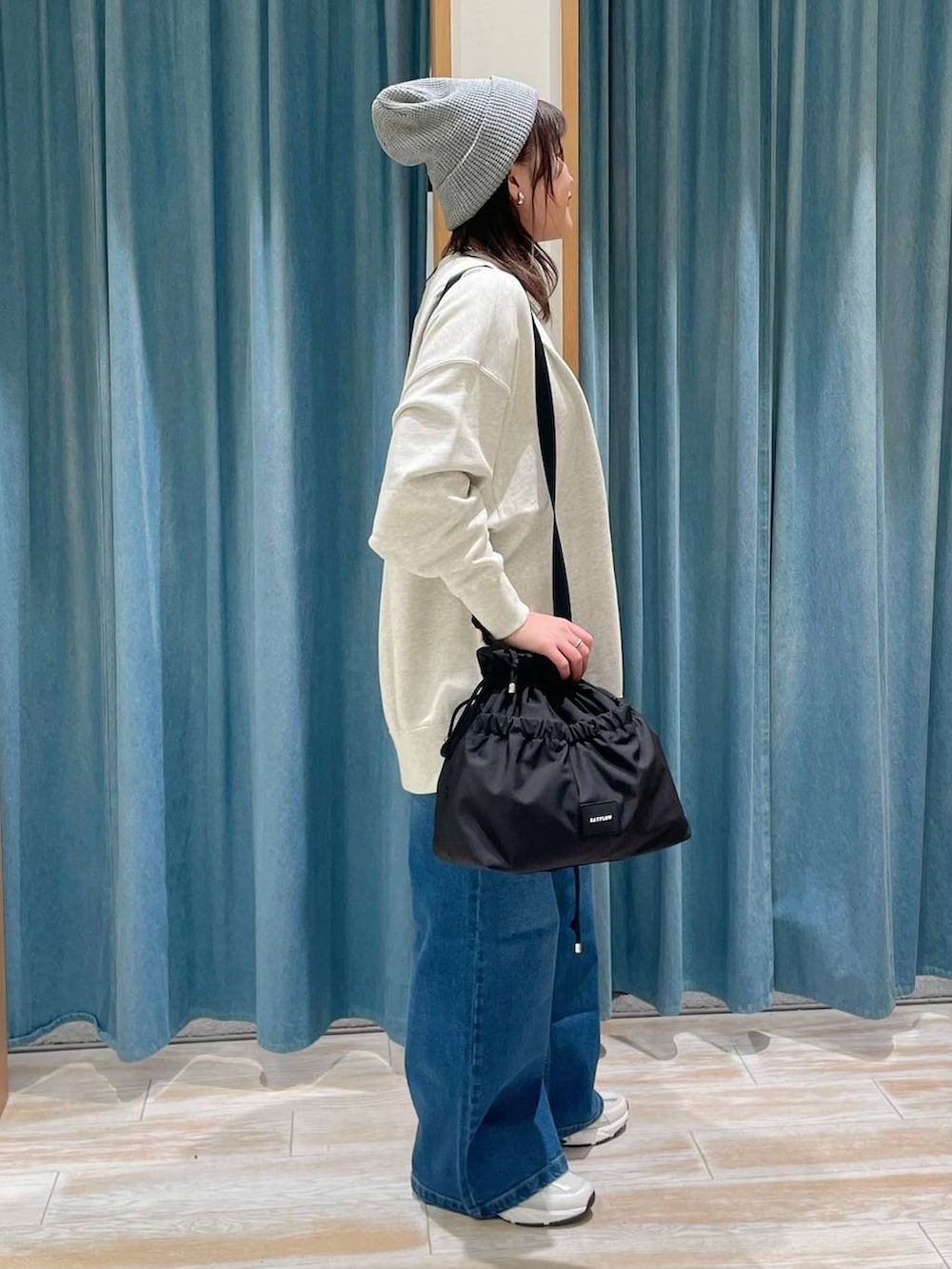 ブラック系のトートバッグ、ベージュ系のスウェット、ブルー系のデニムパンツを着用したレディースの冬コーディネートの3枚目の写真