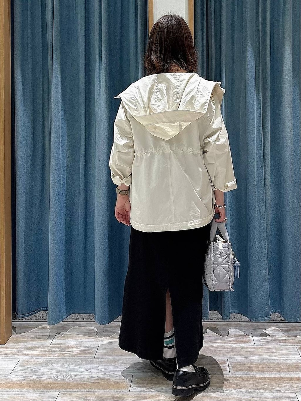 グレー系のショルダーバッグ、ホワイト系のマウンテンパーカー、ブラック系のローファーを着用したレディースの春コーディネートの3枚目の写真