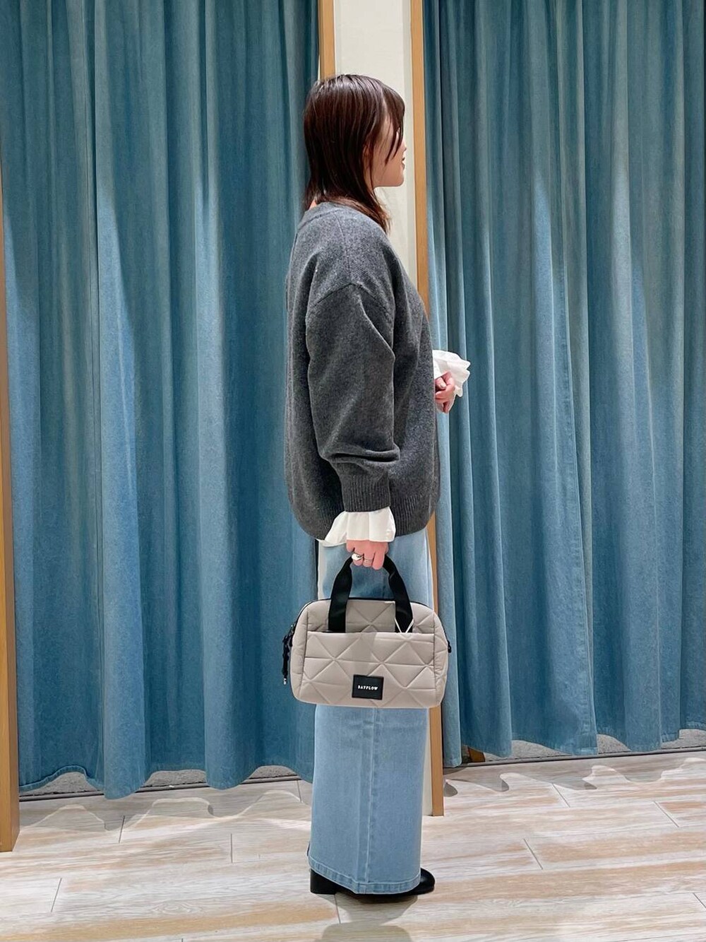 ブラック系のブーツ、グレー系のニット/セーター、ベージュ系のハンドバッグを着用したレディースの冬コーディネートの2枚目の写真