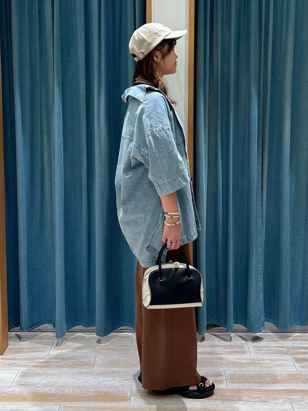 ブラック系のサンダル、ブルー系のシャツ/ブラウス、ブラック系のハンドバッグを着用したレディースの夏コーディネートの2枚目の写真