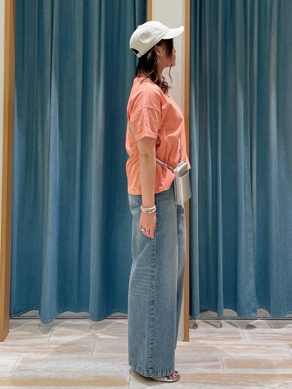 ブラウン系のTシャツ/カットソー、シルバー系のサンダル、ブルー系のデニムパンツを着用したレディースの春コーディネートの2枚目の写真