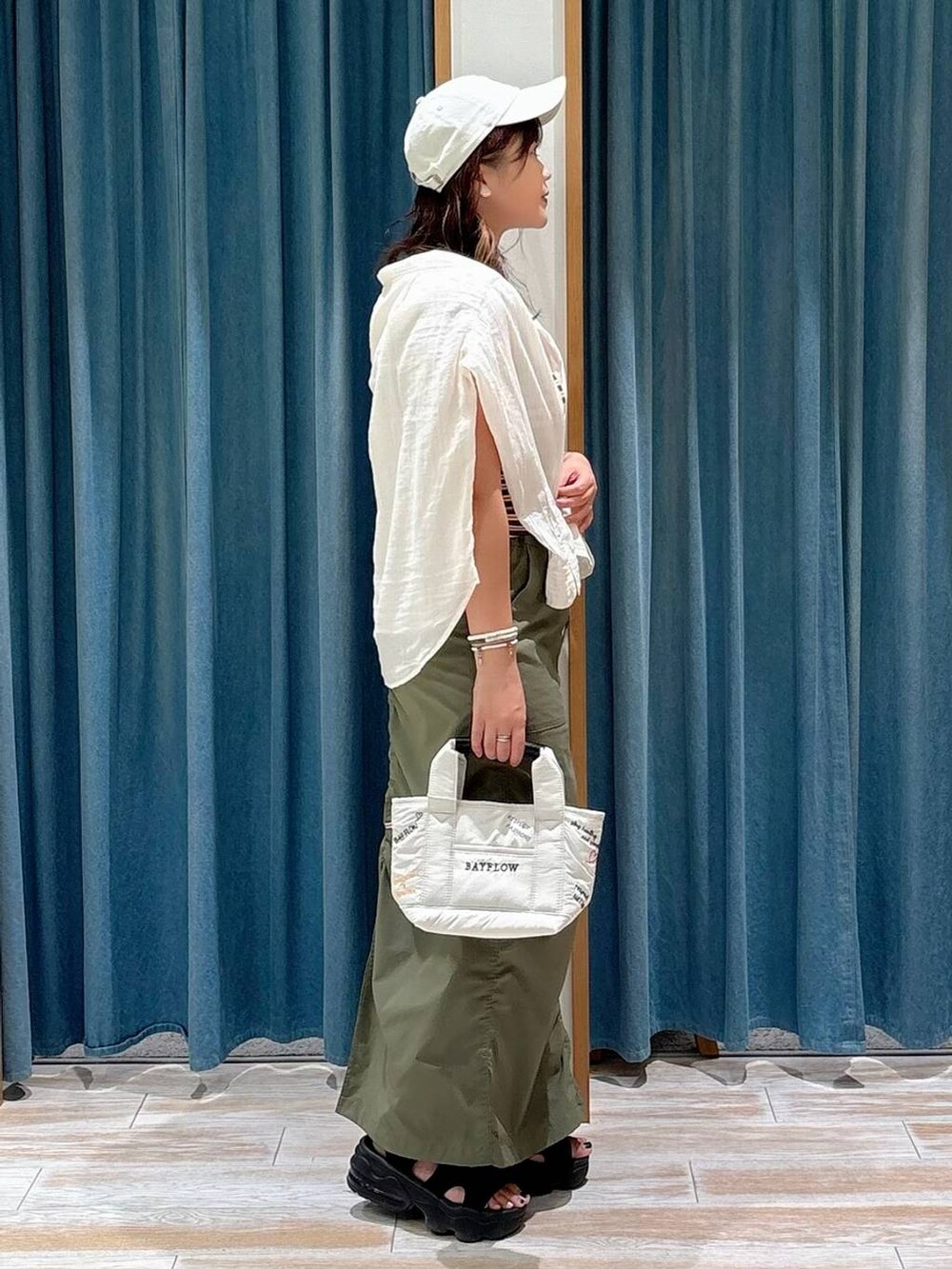 ホワイト系のシャツ/ブラウス、グリーン系のスカート、ホワイト系のトートバッグを着用したレディースの夏コーディネートの2枚目の写真