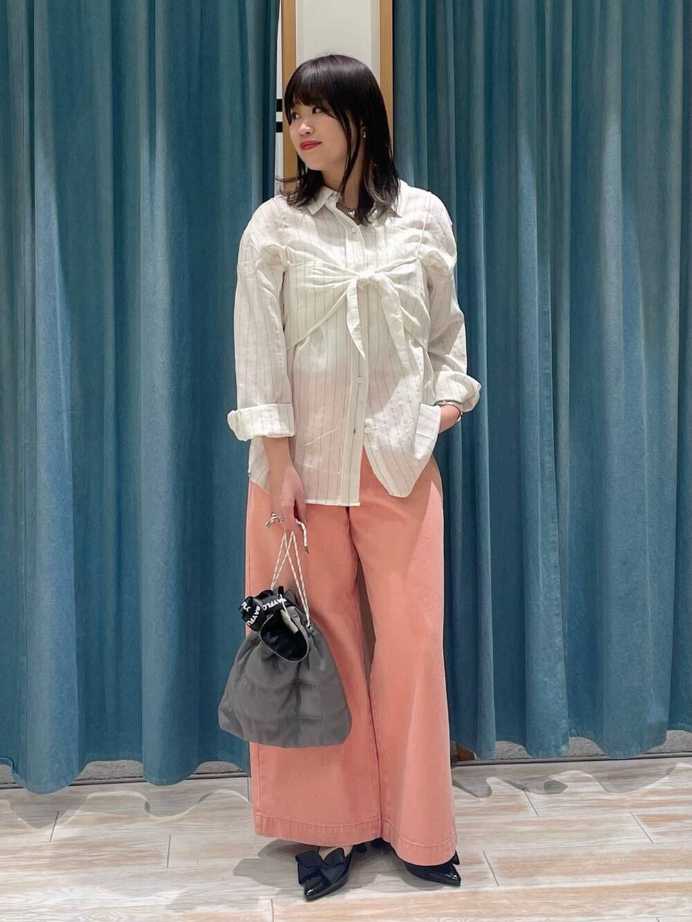 ブラック系のパンプス、グレー系のショルダーバッグ、ピンク系のデニムパンツを着用したレディースの冬コーディネートの4枚目の写真