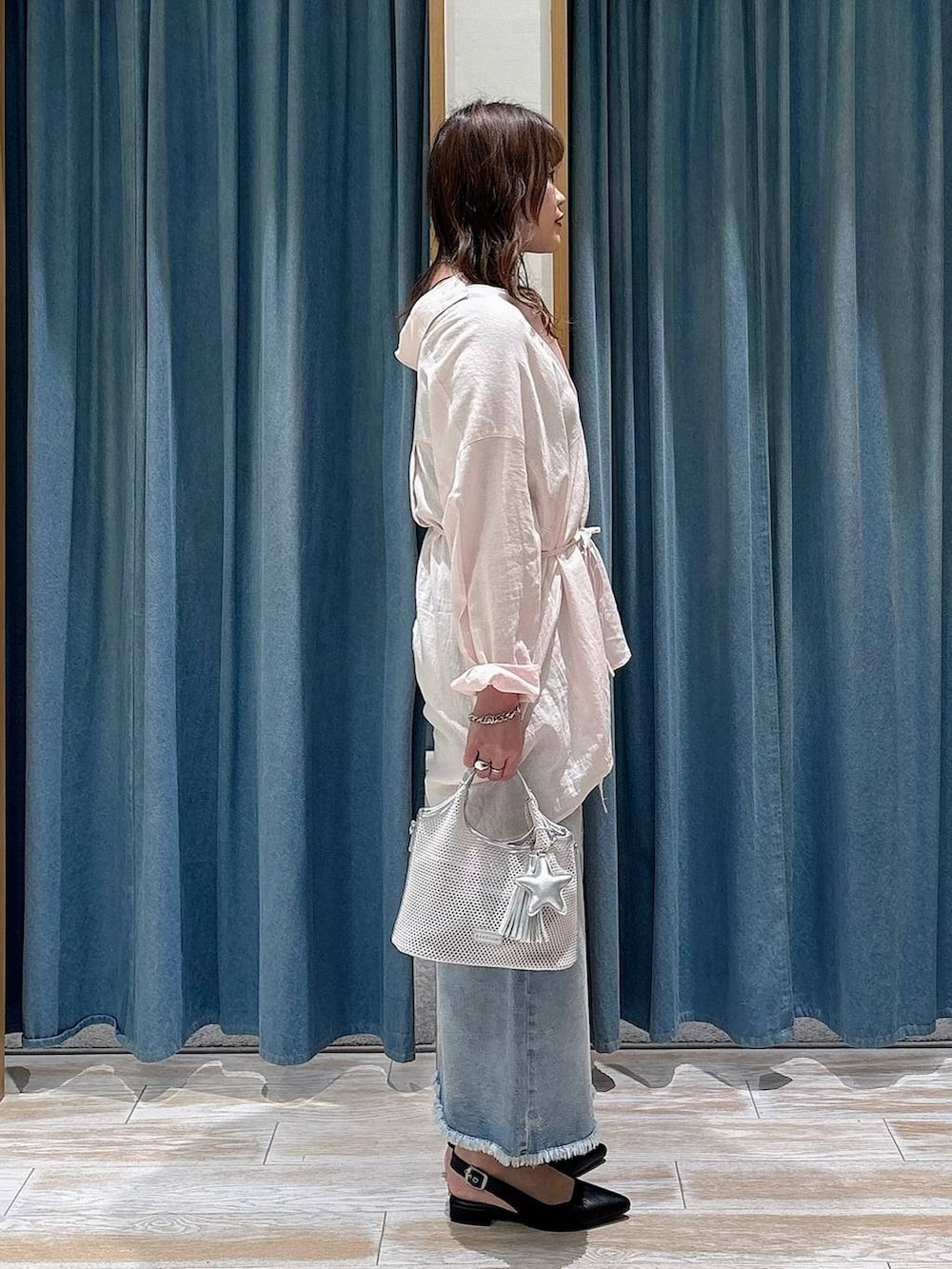 ブラック系のパンプス、ブルー系のデニムスカート、グレー系のショルダーバッグを着用したレディースの春コーディネートの2枚目の写真