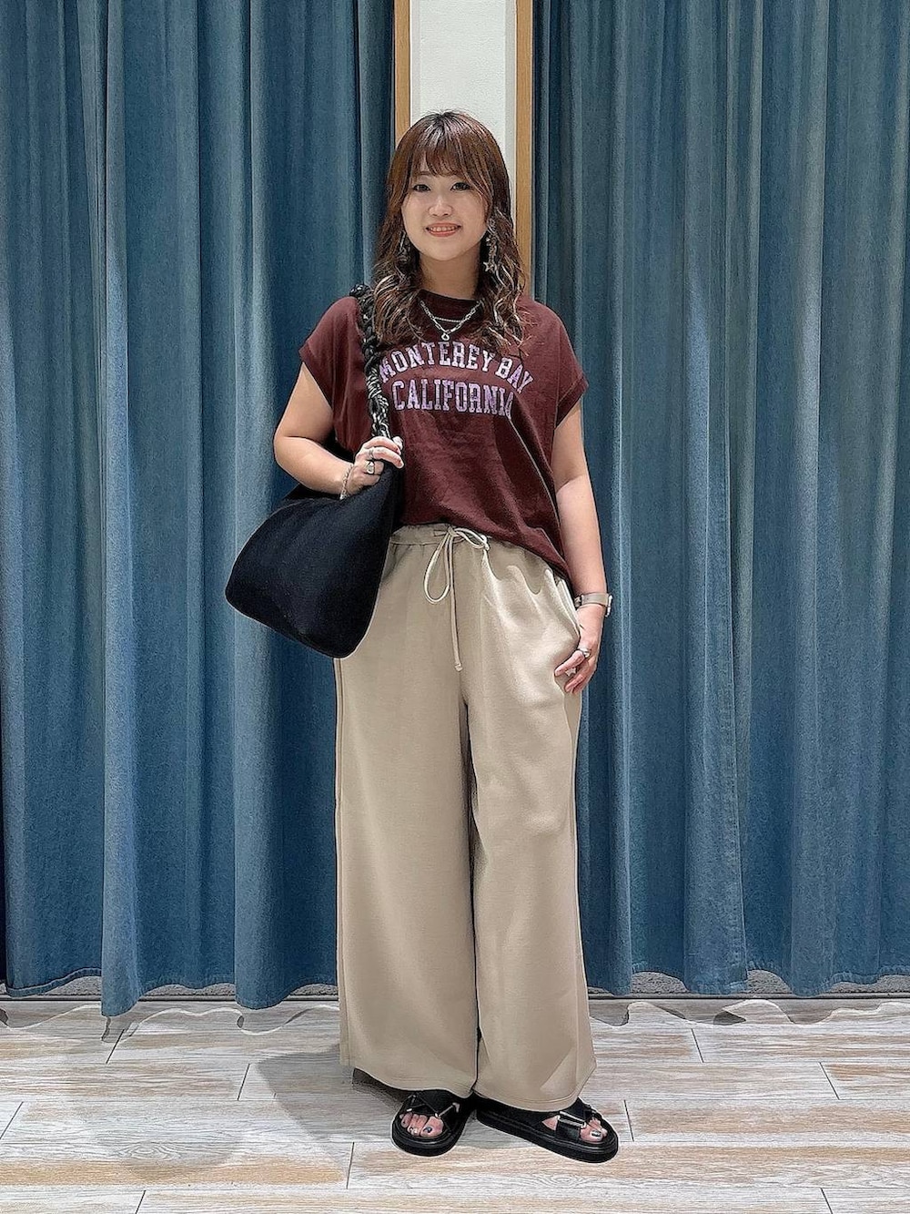 ブラウン系のTシャツ/カットソー、ブラック系のサンダル、ブラック系のトートバッグを着用したレディースの夏コーディネートの4枚目の写真