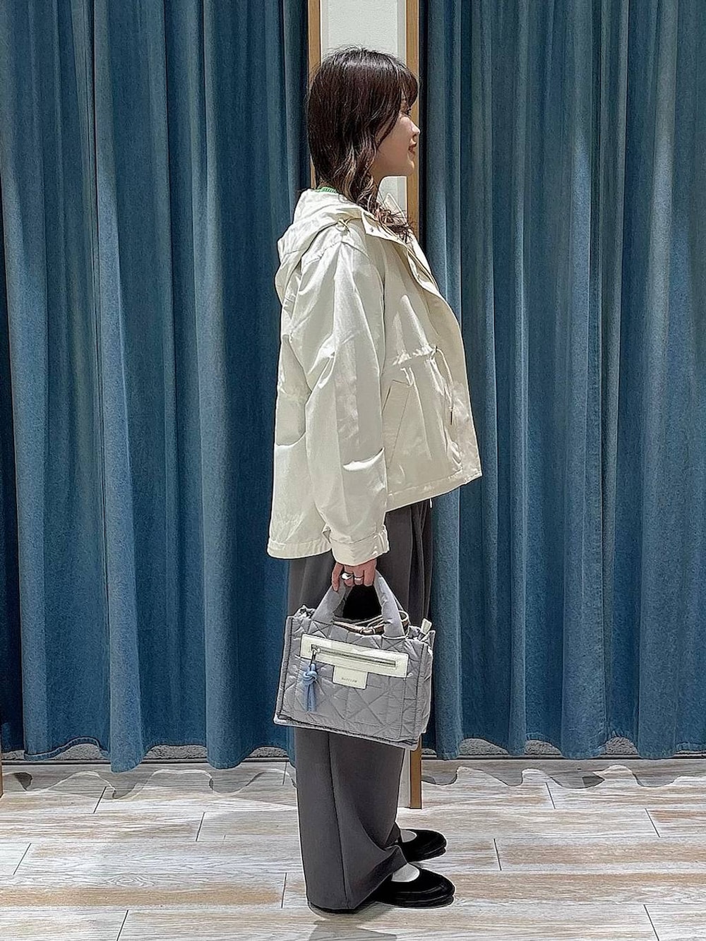 グレー系のショルダーバッグ、ホワイト系のマウンテンパーカー、ブラック系のバレエシューズを着用したレディースの春コーディネートの2枚目の写真