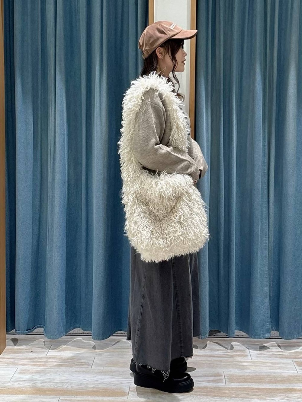 ブラック系のブーツ、ベージュ系のショルダーバッグ、ブラック系のスカートを着用したレディースの秋コーディネートの2枚目の写真