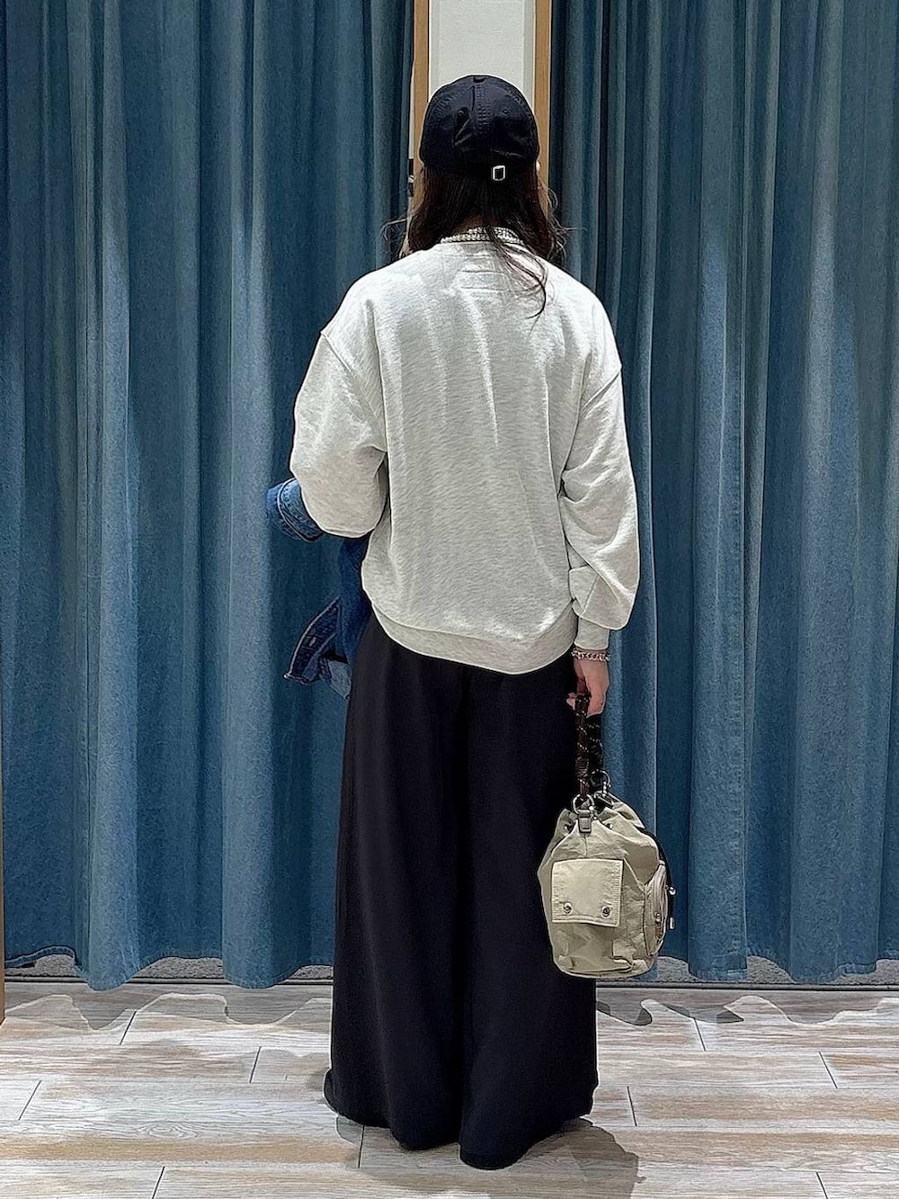 ブラック系のブーツ、ベージュ系のハンドバッグ、ホワイト系のスウェットを着用したレディースの冬コーディネートの3枚目の写真