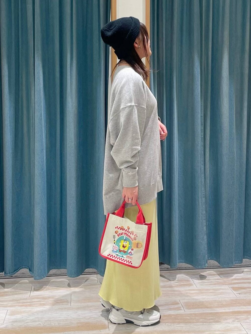 レッド系のトートバッグ、イエロー系のスカート、グレー系のスウェットを着用したレディースの冬コーディネートの2枚目の写真