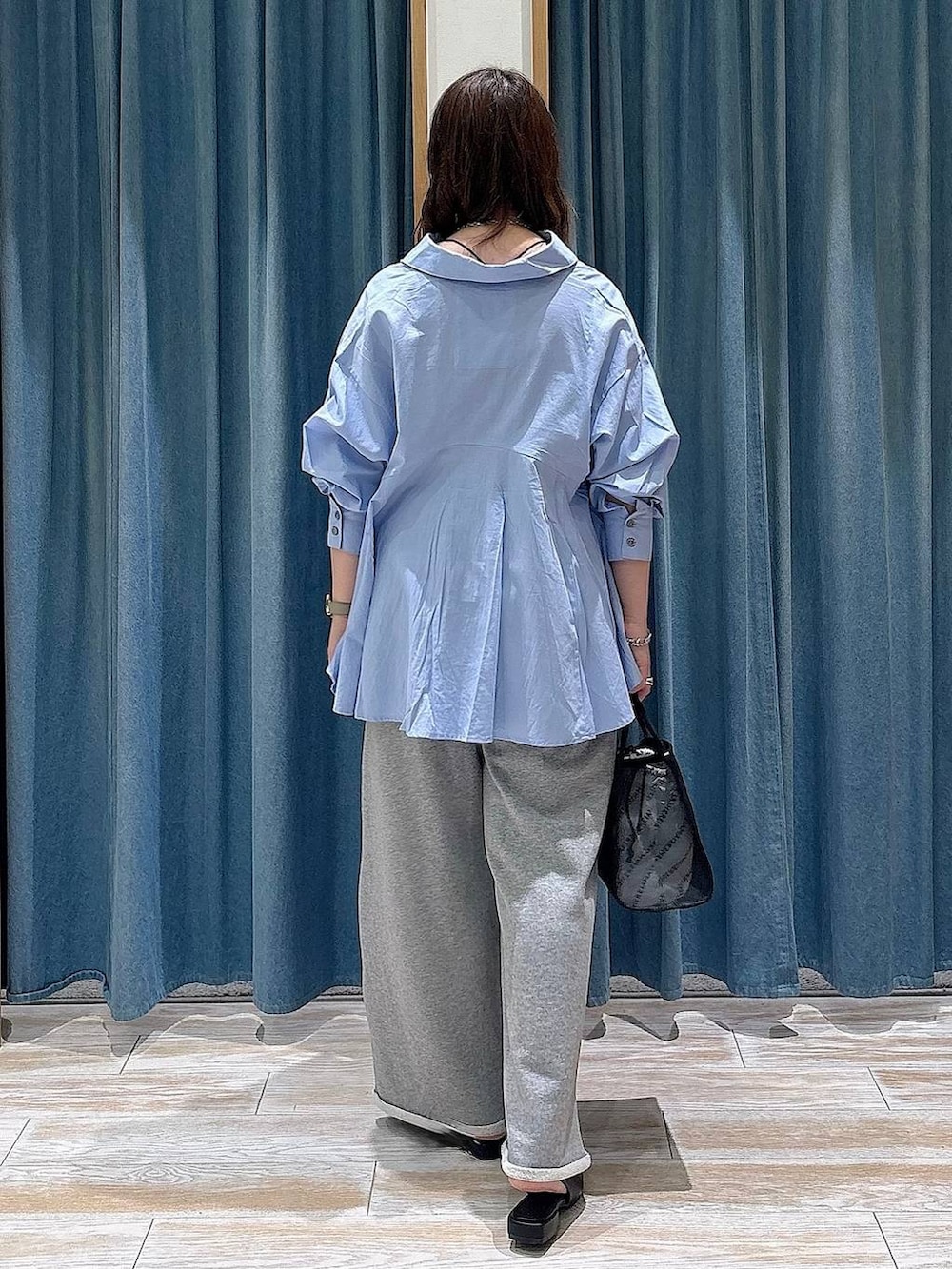 ブラック系のハンドバッグ、ブラック系のパンプス、ブルー系のシャツ/ブラウスを着用したレディースの春コーディネートの3枚目の写真