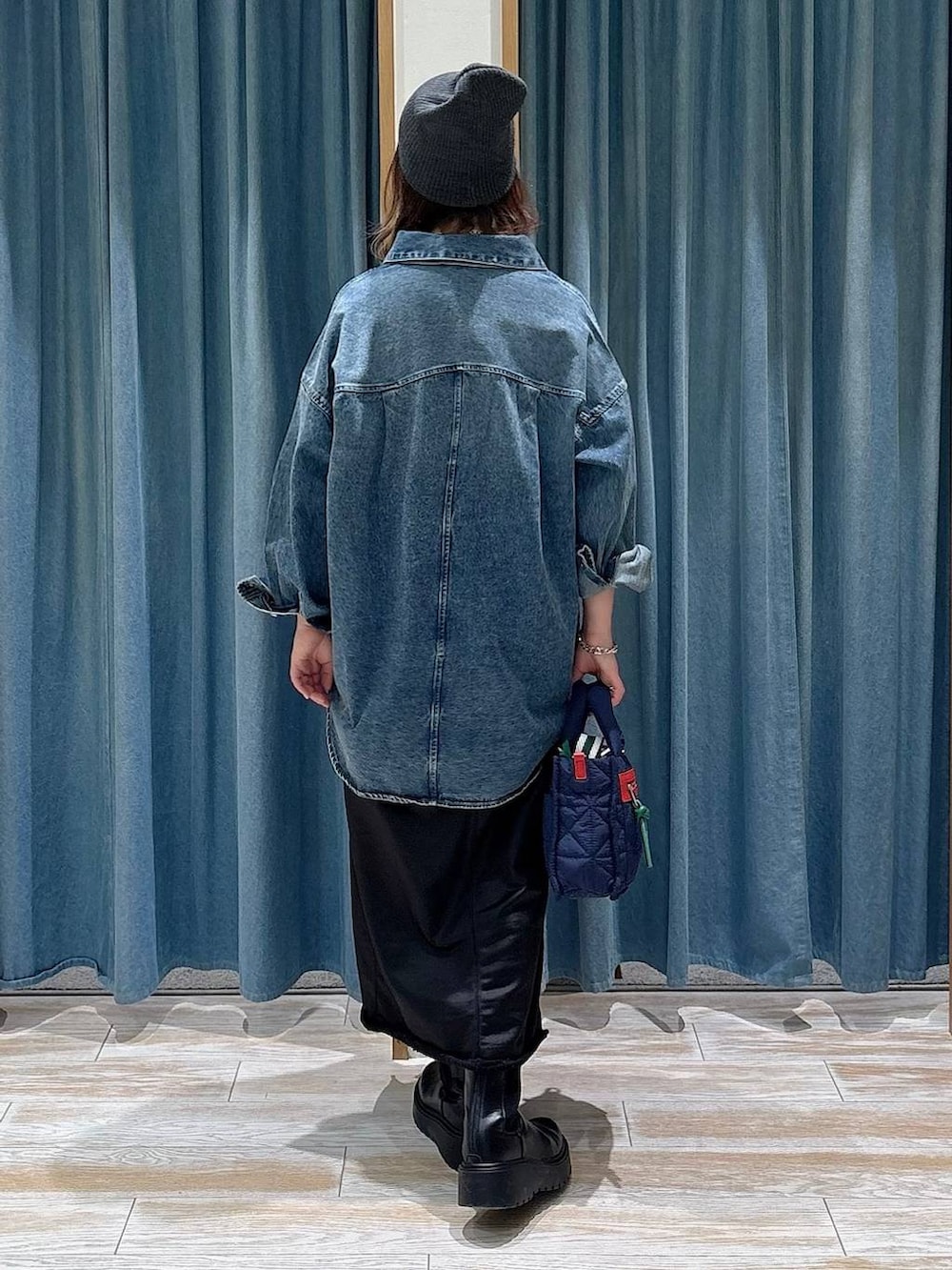 ブルー系のショルダーバッグ、ブラック系のブーツ、ブラック系のスカートを着用したレディースの冬コーディネートの3枚目の写真