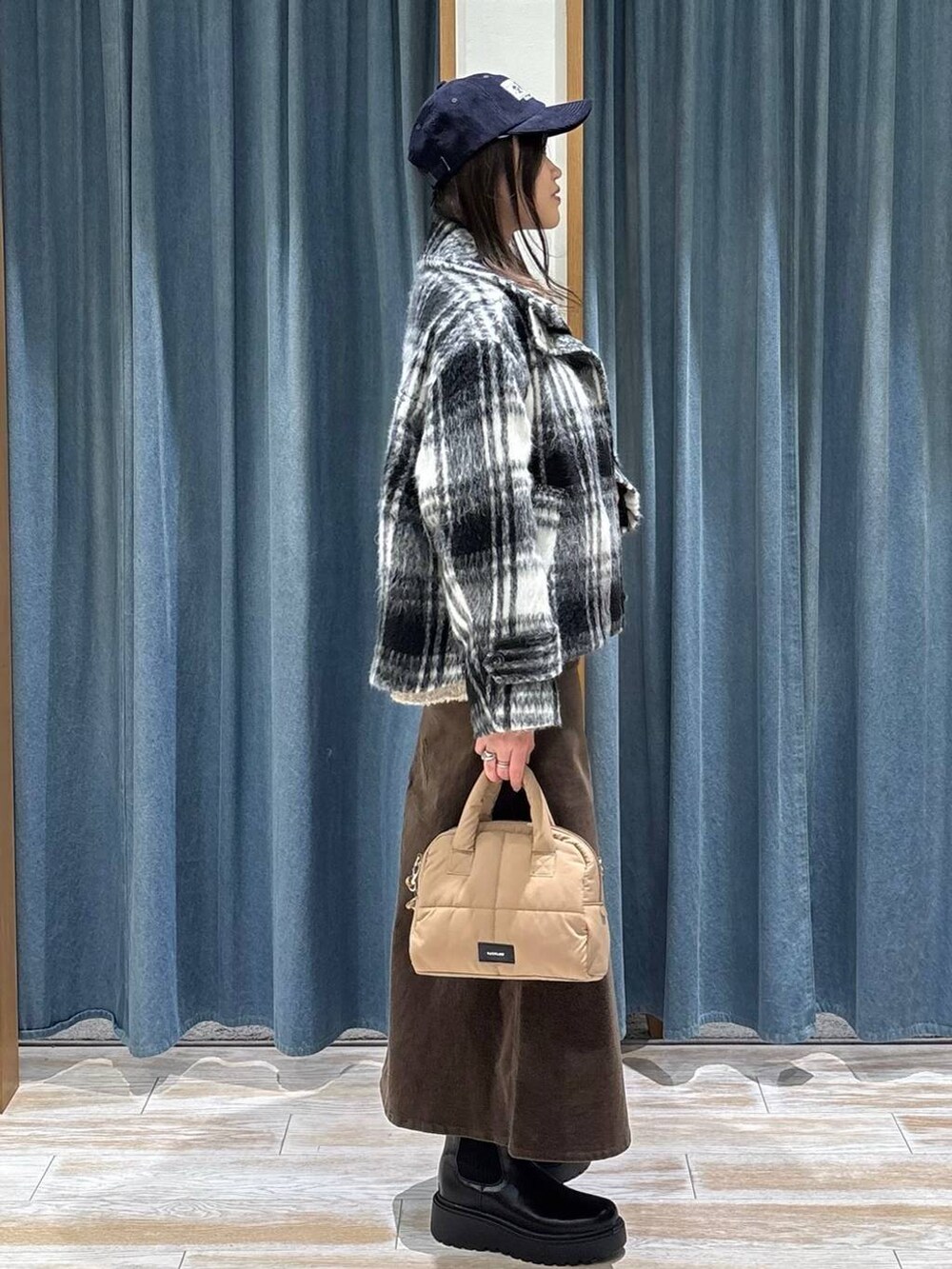 ブラック系のブーツ、ベージュ系のボストンバッグ、ベージュ系のニット/セーターを着用したレディースの冬コーディネートの2枚目の写真