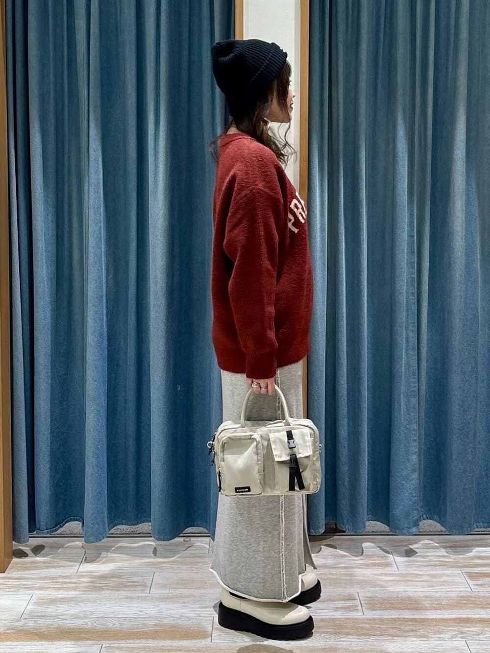 ベージュ系のハンドバッグ、ベージュ系のブーツ、レッド系のニット/セーターを着用したレディースの冬コーディネートの3枚目の写真