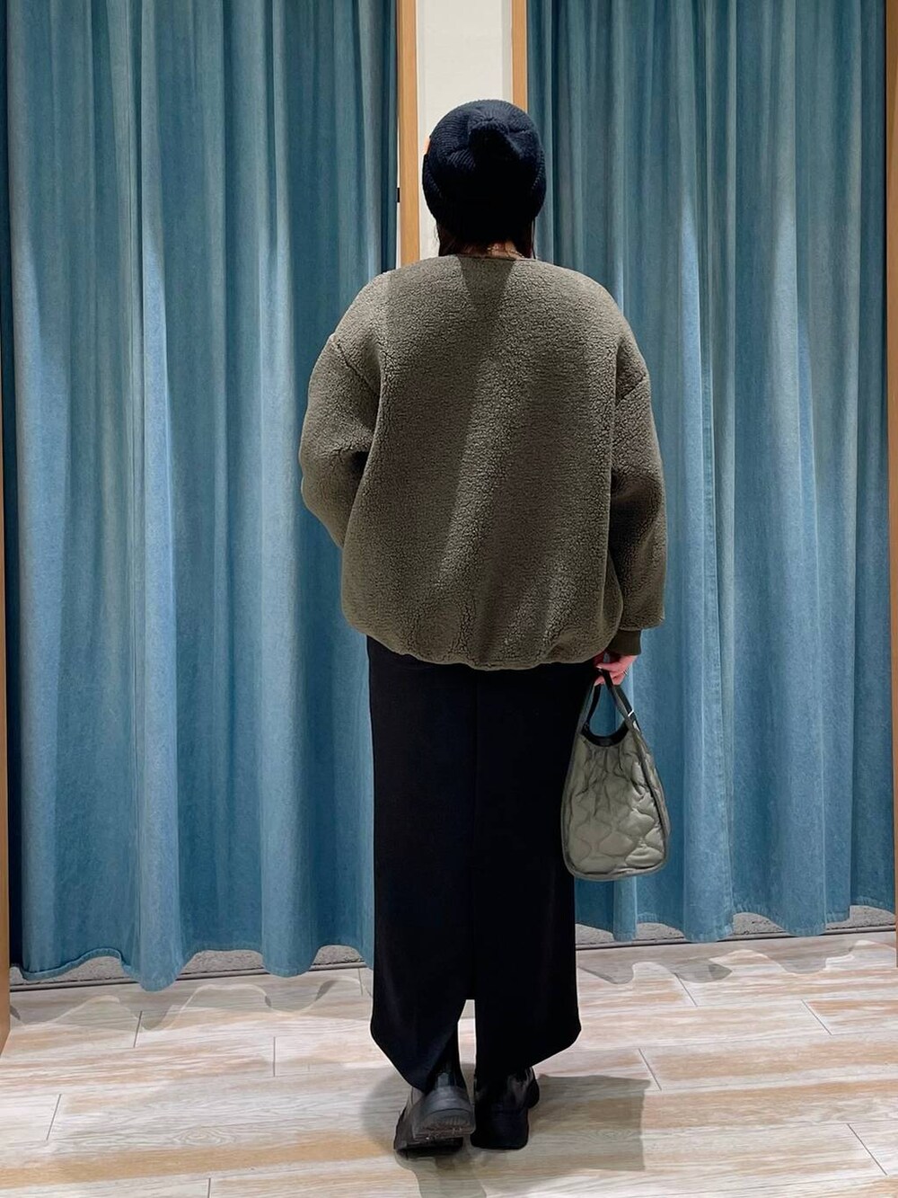 グリーン系のハンドバッグ、ブラック系のブーツ、ホワイト系のTシャツ/カットソーを着用したレディースの冬コーディネートの3枚目の写真