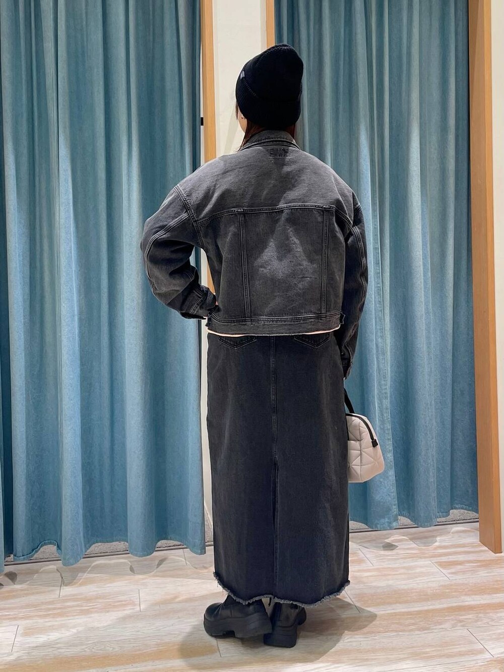 グレー系のデニムジャケット、ブラック系のブーツ、ピンク系のスウェットを着用したレディースの冬コーディネートの3枚目の写真