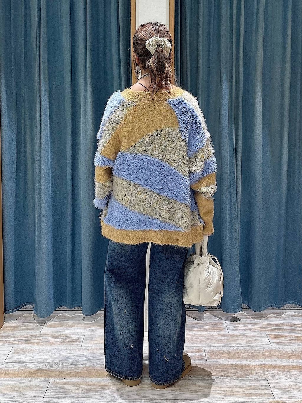 イエロー系のカーディガン/ボレロ、ブルー系のデニムパンツ、ホワイト系のショルダーバッグを着用したレディースの秋コーディネートの3枚目の写真