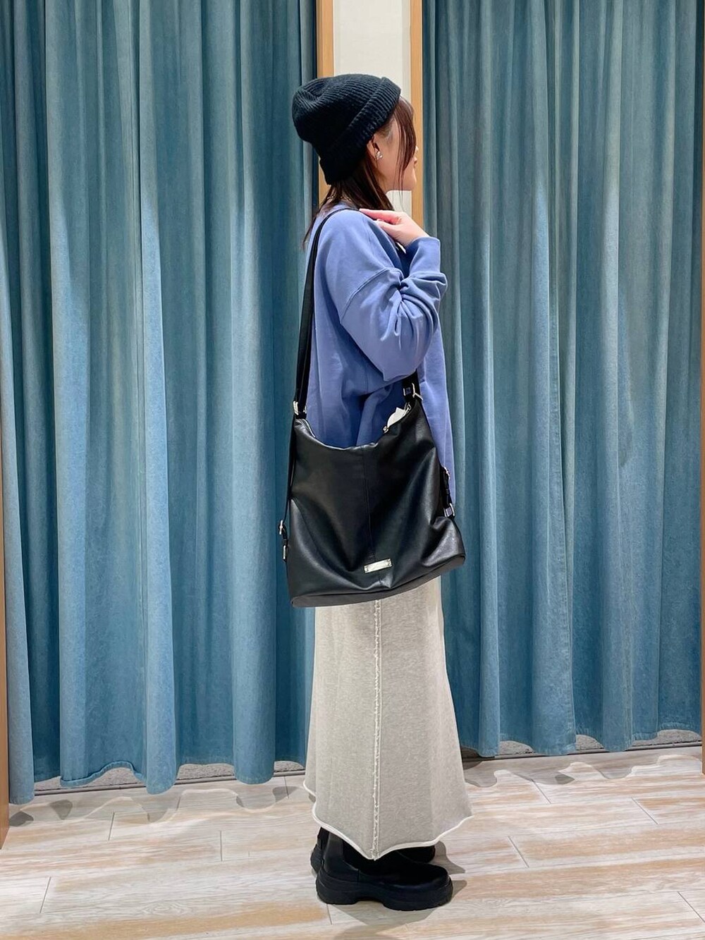 ブラック系のブーツ、ブラック系のショルダーバッグ、ブルー系のスウェットを着用したレディースの冬コーディネートの2枚目の写真