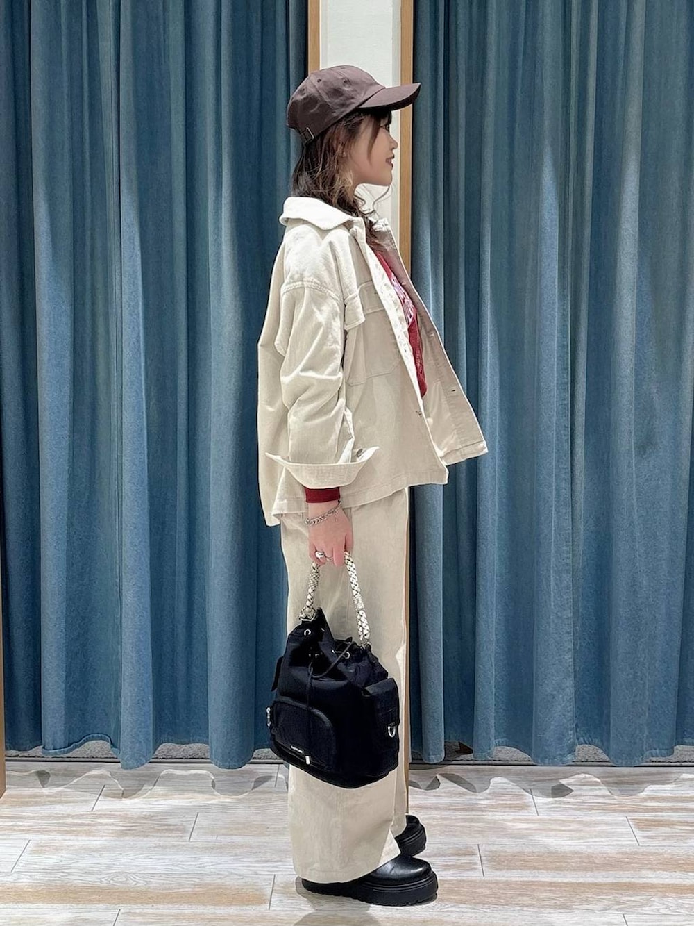 ブラック系のブーツ、ブラック系のハンドバッグ、レッド系のスウェットを着用したレディースの冬コーディネートの2枚目の写真