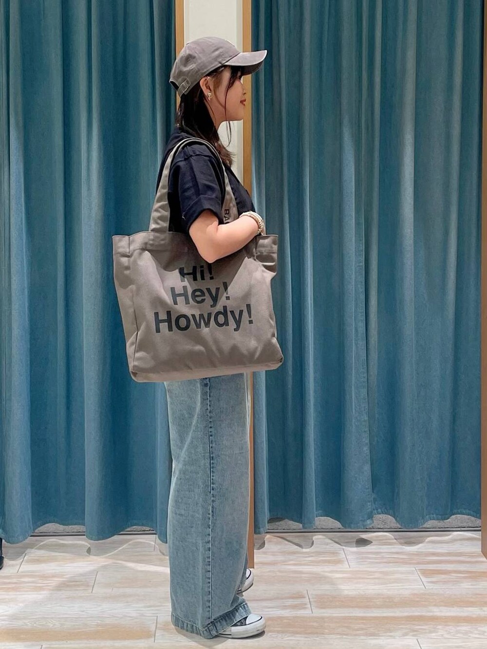 ブルー系のデニムパンツ、グリーン系のトートバッグ、ブラック系のTシャツ/カットソーを着用したレディースの春コーディネートの3枚目の写真